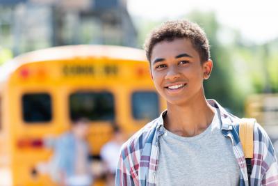 Youth standing in front of a school bus