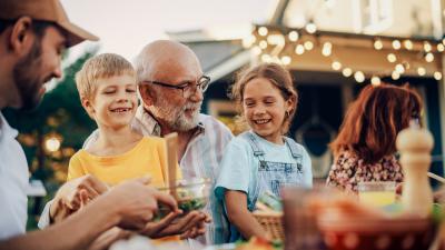 Adult males with children sharing a picnic type meal