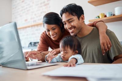 Husband and wife looking at computer with toddler