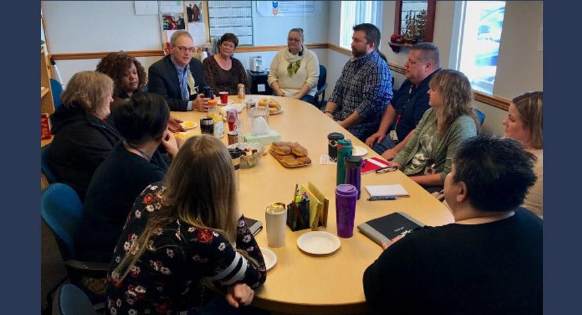 Ross sitting at table with staff