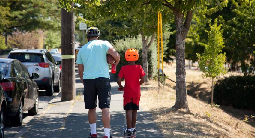 adult walking next to child on bike