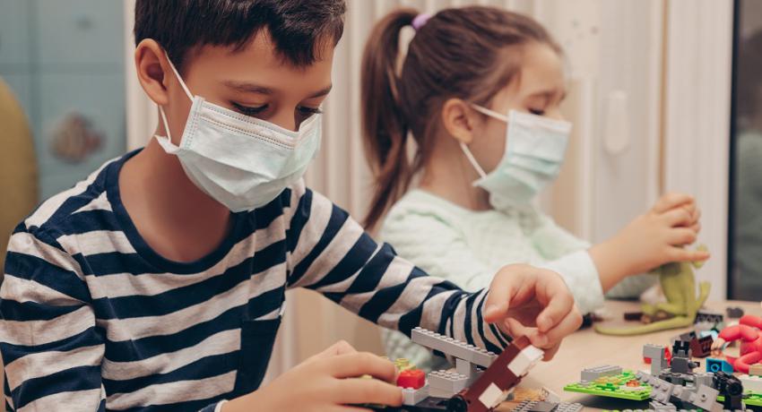 Children playing with Legos while wearing face masks.