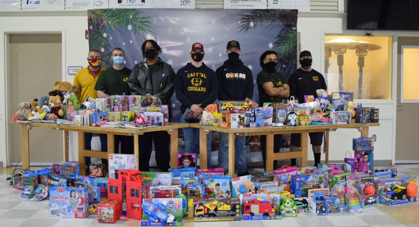 GHS youth and CHS football players gather around a large pile of donated toys. 