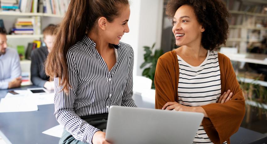 Adult talks to youth holding a laptop. 