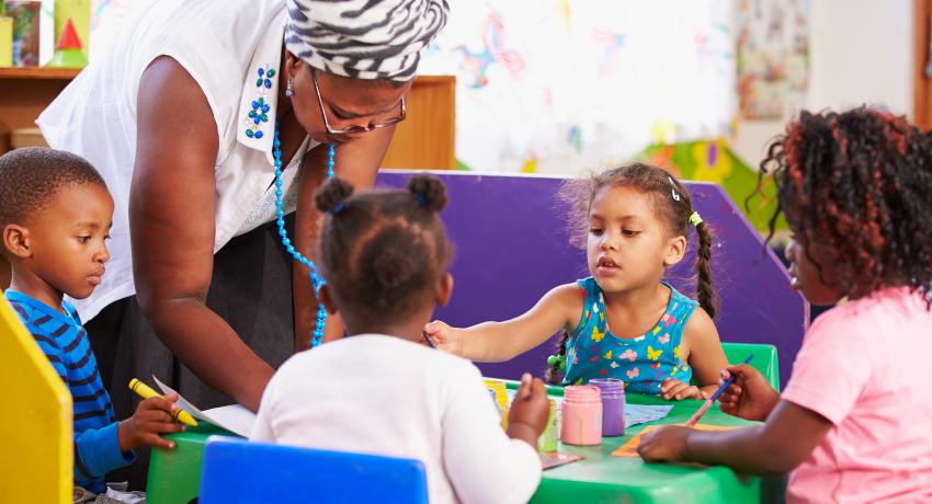 preschool teacher with children painting