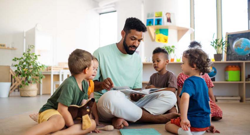 Man sitting on floor reading to children