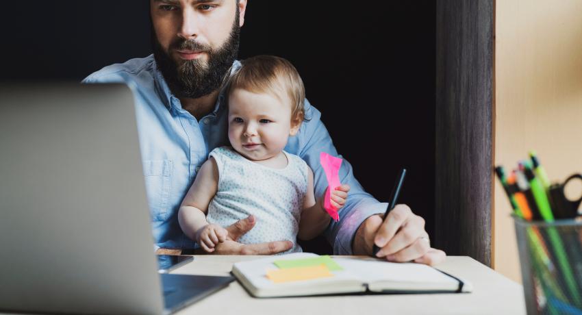 father on laptop with child in lap