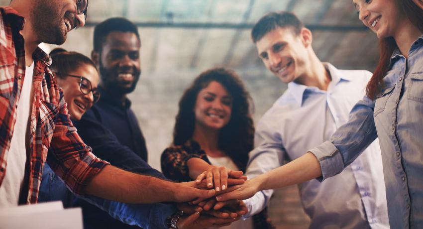 Group of people putting hands together in spirit of teamwork