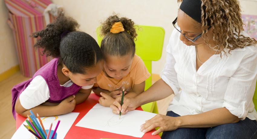 Children reading and writing with teacher