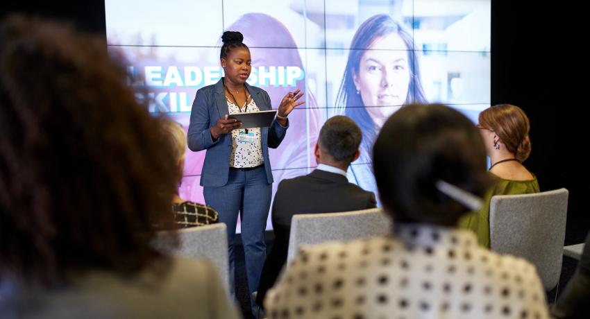 Woman presenting for audience in front of big screen