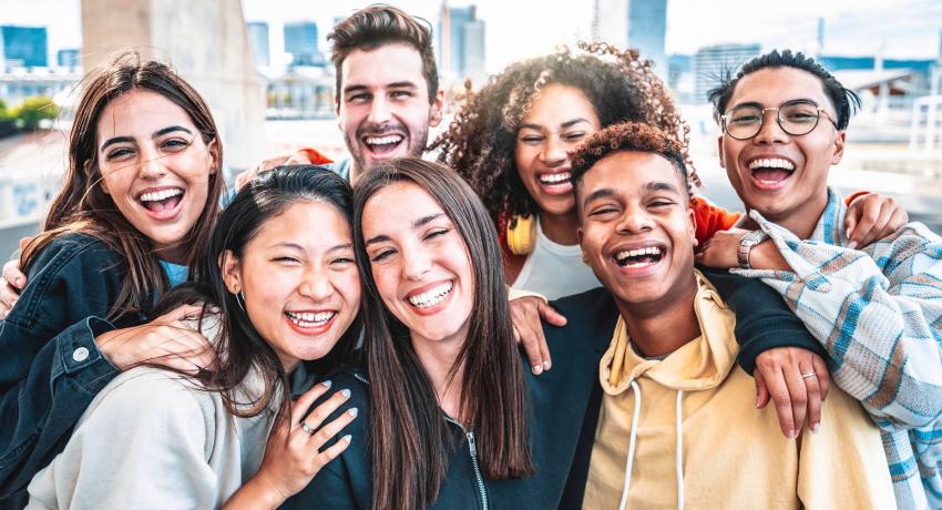 a diverse group of teens crowded around smiling at the camera