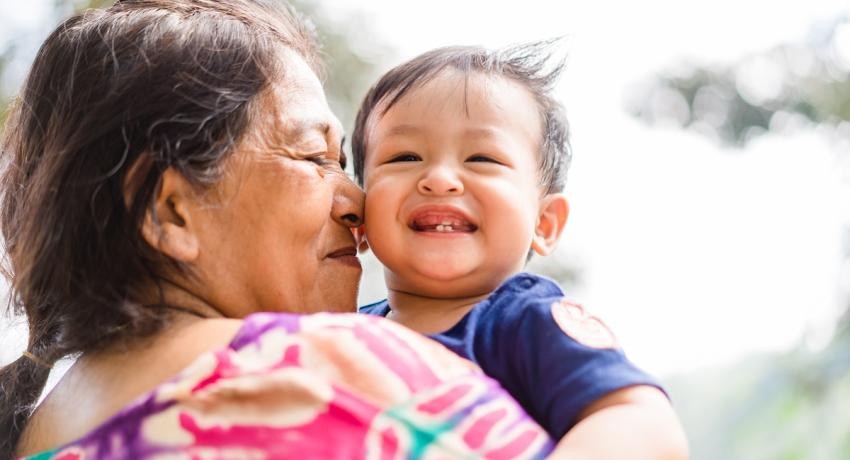 Native American grandma holding and hugging young grandson. Granson is smiling. 